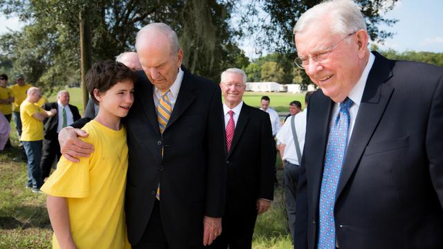 Des dirigeants de l'Église offrent de l'encouragement aux victimes des inondations et aux volontaires en Louisiane, le 3 septembre 2016. Russell M. Nelson met son bras autour d'un jeune bénévole des Mains serviables.