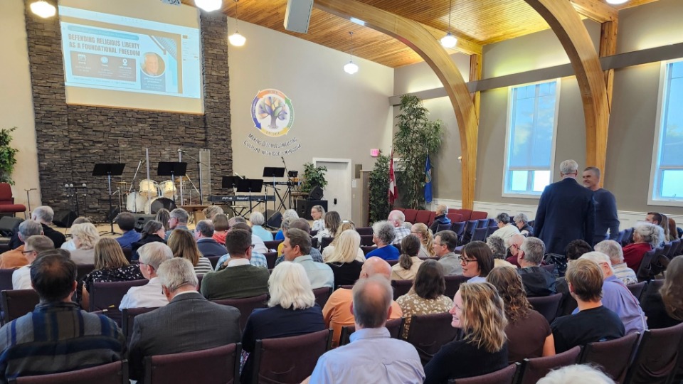 3. (À l’extrême droite) John Young salue le pasteur Zwartbol avant le troisième Symposium annuel sur la liberté de religion à Lethbridge (Alberta), le 16 septembre 2026.